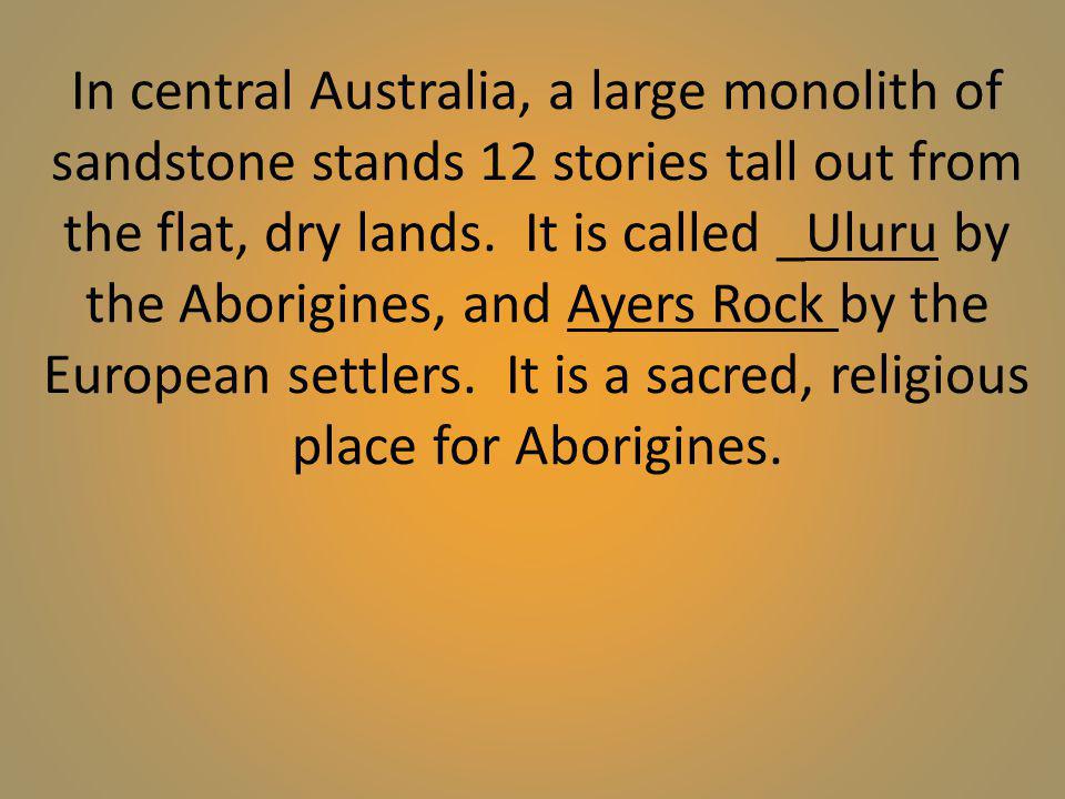 In central Australia, a large monolith of sandstone stands 12 stories tall out from the flat, dry lands.
