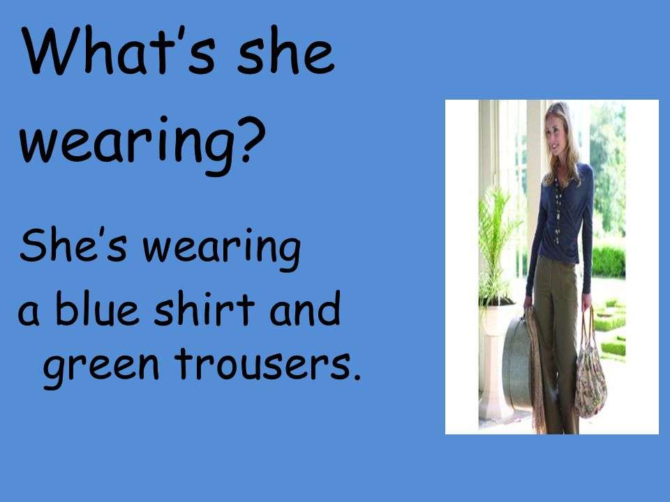 What’s she wearing She’s wearing a blue shirt and green trousers.